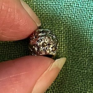 Pandora silver charm with flower design, approximately 1/3rd of an inch around.